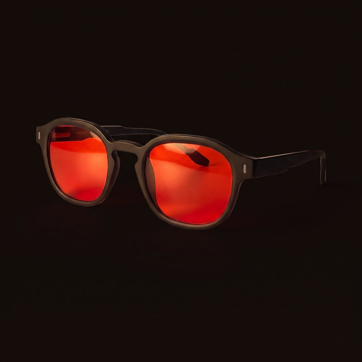 Lunettes à verres rouges sur fond sombre, éclairées par une lampe