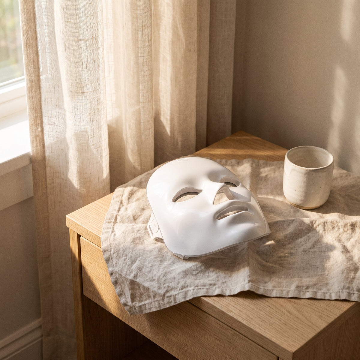 Masque LED visage rigide blanc dans un intérieur clair, lin et bois